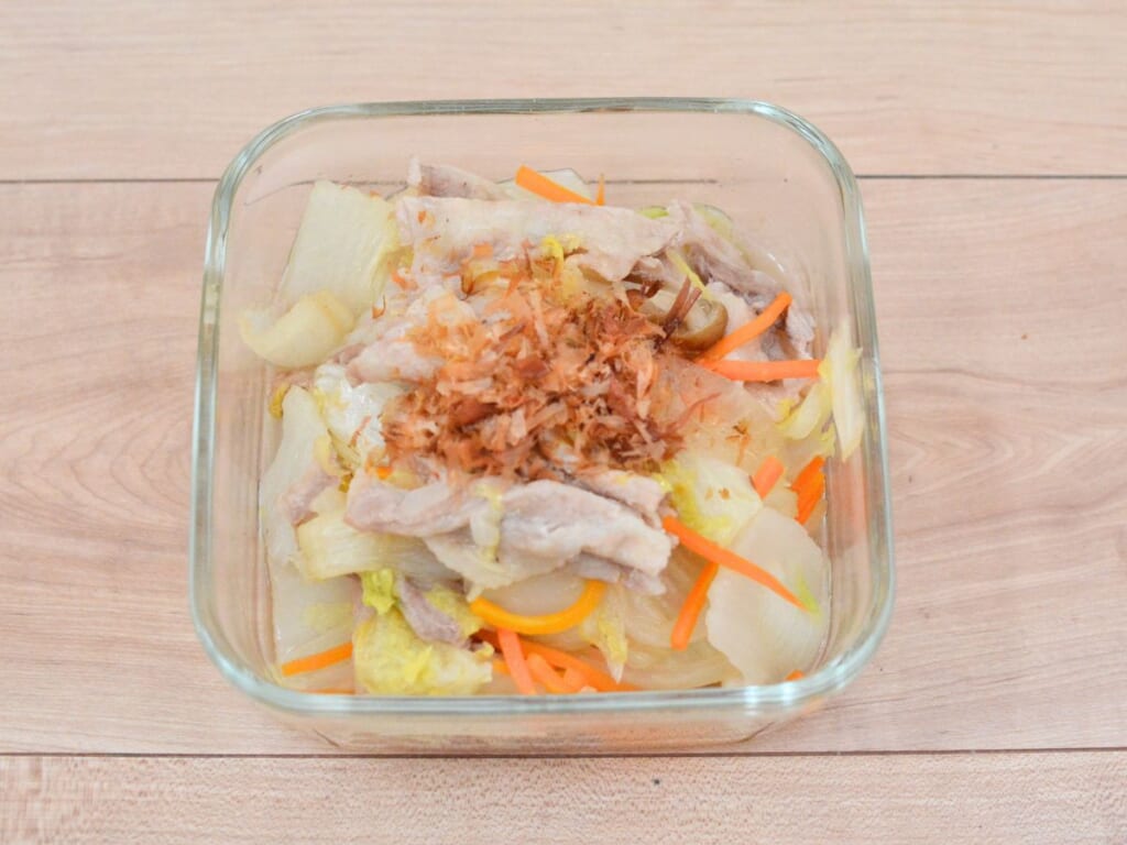保存容器に盛りつけた、完成した国産野菜とお米育ち豚の蒸し料理。かつお節をのせている