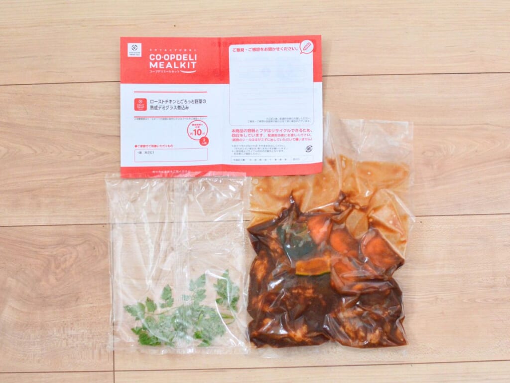 コープデリのミールキット「ローストチキンとごろっと野菜の熟成デミグラス煮込み」の届いた中身。ソースに漬けた鶏肉と野菜の袋、香草の袋、レシピカード