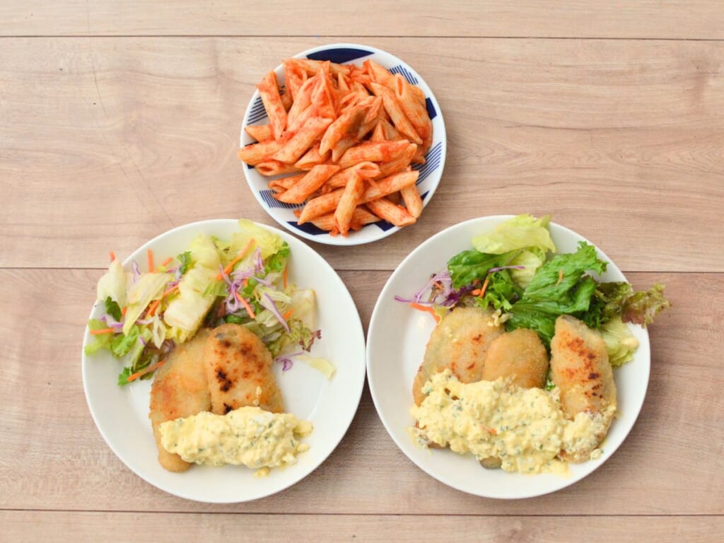 2皿に盛りつけた完成したサーモンフライのタルタルソースがけと、ナポリタンペンネサラダ